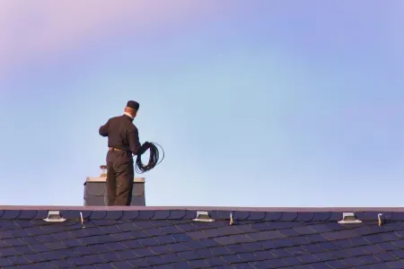 Kominiarz na dachu. Stoi tyłem.