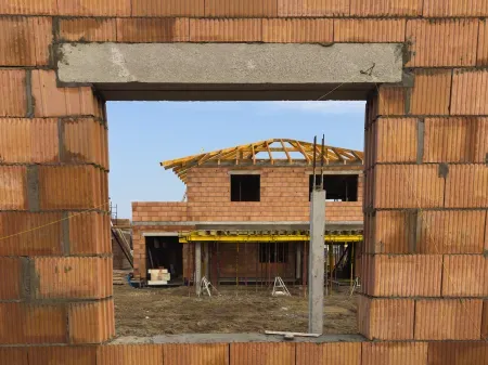 Otwór na okno z widokiem na dom w budowie.